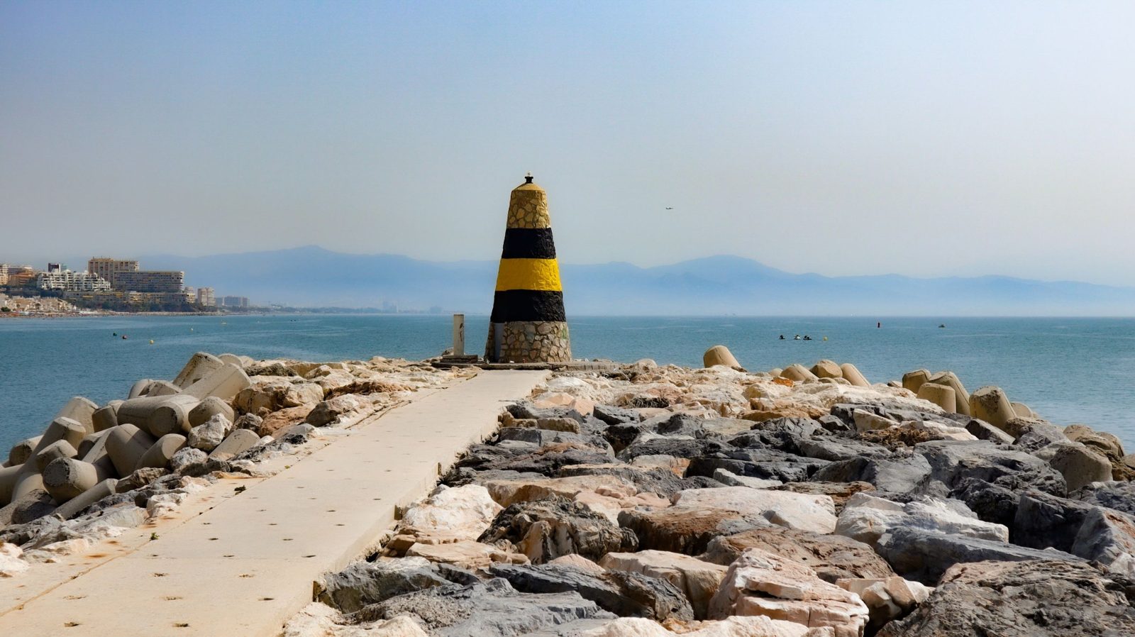 Striped beacon at the end of a breakwater on the Málaga West coast