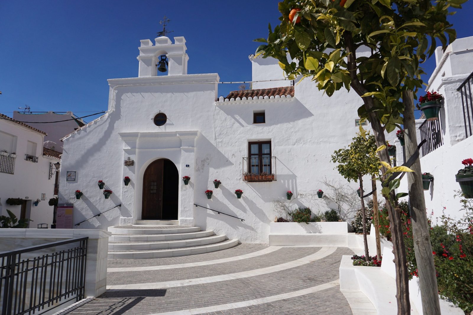 Whitewashed chapel and orange tree in a Mijas square